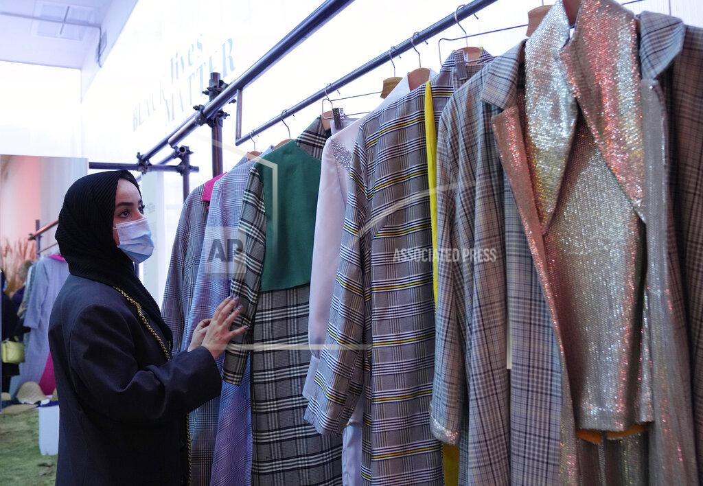 Antonio Calanni Fashion designer Zineb Hazim, from Morocco, touches her creations, part of the Black Lives Matter Spring Summer 2022 collective fashion event, unveiled during the Milan Fashion Week, in Milan, Italy, Tuesday, Sept. 21, 2021. (AP Photo/Antonio Calanni)