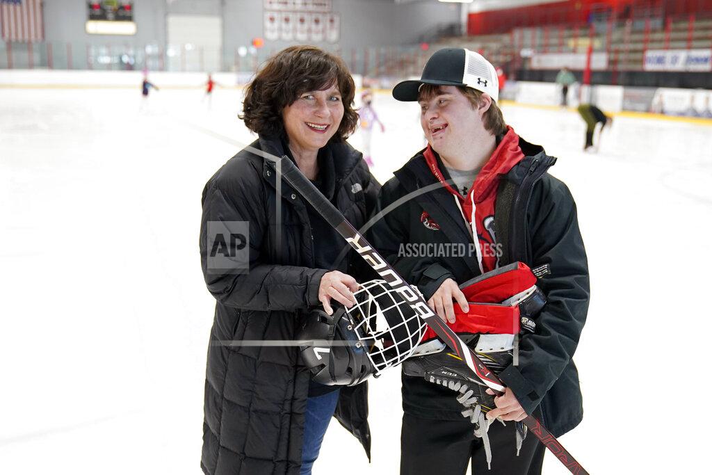 Suzy Lindeberg poses with her 20-year-old son John on a hockey rink, Tuesday, Feb. 9, 2021 in Stillwater, Minn. John, who has Down Syndrome, can't spend as much time at the rink as he used to since he is at a higher risk for hospitalization or death if he caught COVID-19, but his mother and other advocates worry that the state of Minnesota has placed people with disabilities too far down the priority list. (AP Photo/Jim Mone)