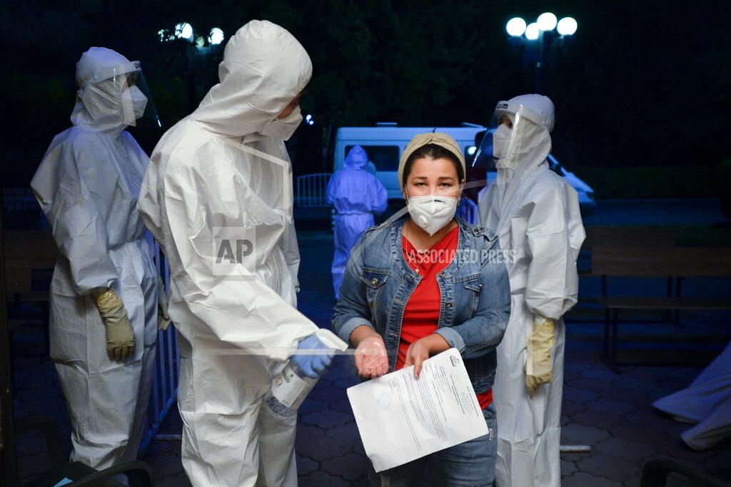 Vladimir Voronin A medical worker disinfects hands of a patient who is suspected of having the coronavirus as she enters a hall of a restaurant that was converted into a night-time clinic in Bishkek, Kyrgyzstan, Wednesday, July 22, 2020. The restaurant in central Bishkek was converted into a night-time clinic an effort to support the impoverished country's health care system, struggling with the coronavirus outbreak. Doctors and nurses from other facilities work there and treat people between 8 p.m. and 8 a.m. (AP Photo/Vladimir Voronin)
