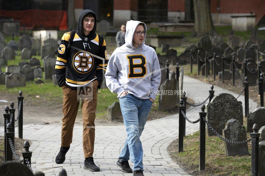 Michael Dwyer Matthew Hammerschmidt, right, and Dasan Zahn, both of Bismarck, N.D., visit Old Granary Burying Ground in Boston, Saturday, March, 14, 2020. Fans of the Boston Bruins, they had flown in specifically for Saturday night's game against the Toronto Maple Leafs. The pair said they learned that the NHL had suspended play due to concern about the coronavirus just as the plane was touching down in Boston. For most people, the new coronavirus causes only mild or moderate symptoms, such as fever and cough. For some, especially older adults and people with existing health problems, it can cause more severe illness, including pneumonia. The vast majority of people recover from the new virus. (AP Photo/Michael Dwyer)