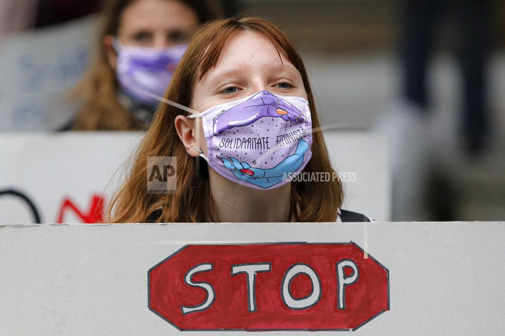 Vadim Ghirda Women, wearing masks against the COVID-19 infection that read "Feminist Solidarity", hold banners during a protest in Bucharest, Romania, Sunday, Oct. 25, 2020, against rising levels of violence against women and the ineffectiveness of restraining orders during and after the lockdown period imposed by authorities to control the pandemic. Romania, a European Union member state, has no proper legal framework to combat domestic violence against women, with police unable to intervene if acts of violence inside a couple's home. (AP Photo/Vadim Ghirda)