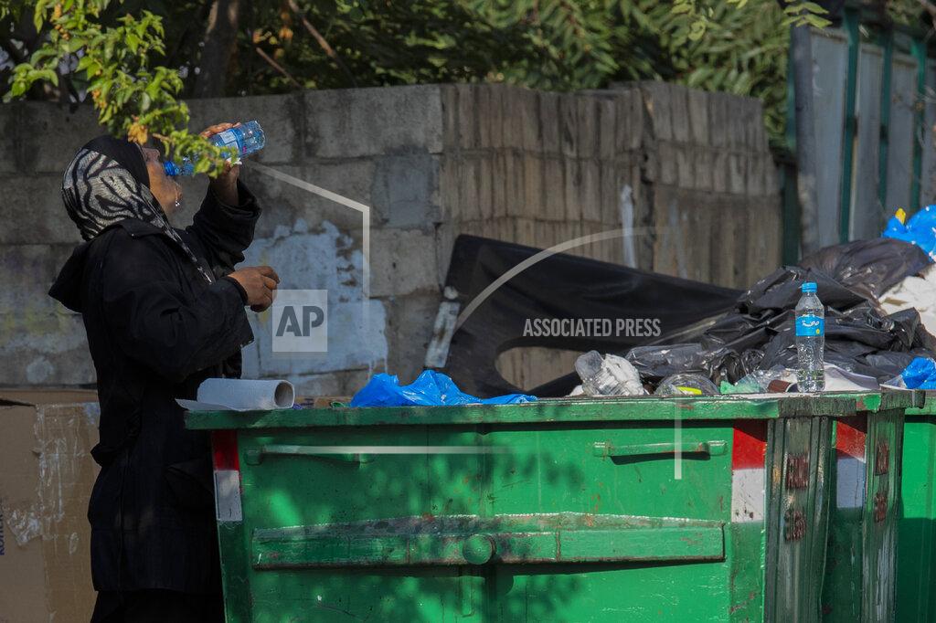 Hassan Ammar A homeless woman drinks water from a garbage dumpster in Beirut, Lebanon, Thursday, July 23, 2020. Lebanon should quickly form a reform-minded government to carry out badly needed reforms to help get the tiny country out of its severe economic crisis where the Real GDP growth is projected to contract nearly 20% in 2020 and a crash in local currency led to triple-digit inflation rates, the World Bank said Tuesday. (AP Photo/Hassan Ammar)