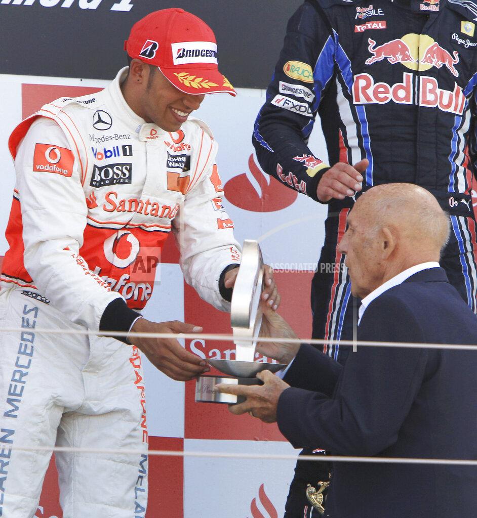 Mark Baker FILE - In this file photo dated Sunday, July 11, 2010, McLaren Formula One driver Lewis Hamilton, left, receives his trophy for second place from legendary British racing driver Stirling Moss at the British Formula One Grand Prix in Silverstone, England. Stirling Moss has died at the age of 90, according to an announcement Sunday April 12, 2020, from his family. (AP Photo/Mark Baker, FILE)
