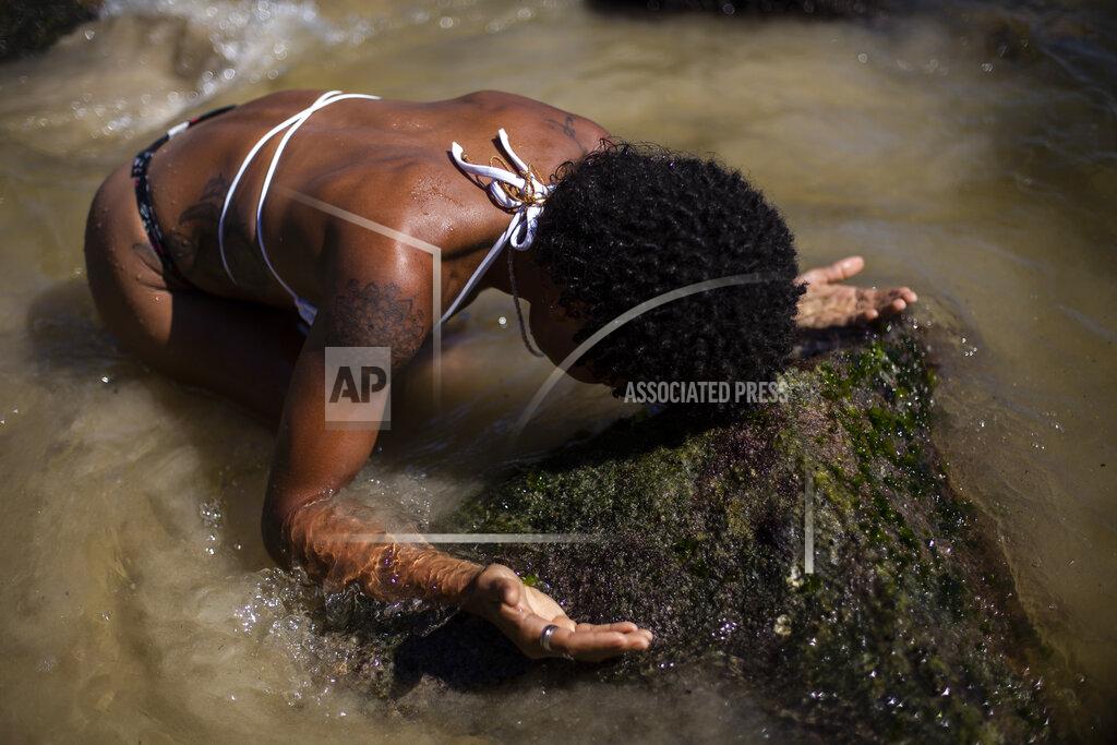 Bruna Prado Shirley Azedi, who said she's lost work as a housekeeper due to the COVID-19 pandemic, prays during a ceremony in honor of the Goddess of the Sea Yemanja on Praia Vermelha beach to mark the end of the year in Rio de Janeiro, Brazil, on New Year's Eve, Thursday, Dec. 31, 2020. Beaches will be closed on the night of new year's, to help curb the spread of the new coronavirus. (AP Photo/Bruna Prado)
