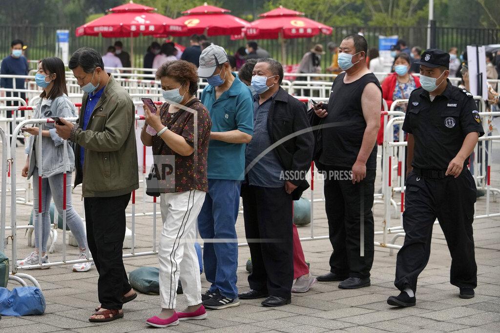 Andy Wong A security guard watches residents wearing face masks to help curb the spread of the coronavirus line up to receive the Sinopharm COVID-19 vaccine at a vaccination center in the Central Business District in Beijing, Wednesday, June 2, 2021. After a slow start, China is now doing what virtually no other country in the world can: harnessing the power and all-encompassing reach of its one-party system and a maturing domestic vaccine industry to administer shots at a staggering pace. (AP Photo/Andy Wong)