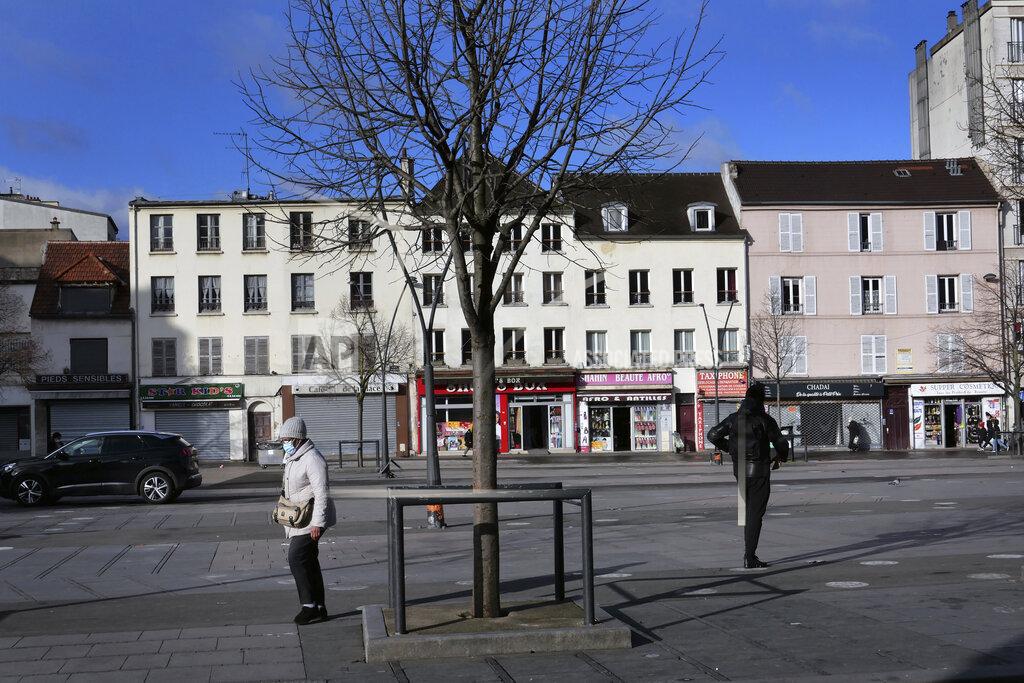 Christophe Ena People walk in a Saint-Denis street, outside Paris, Monday, Jan. 25, 2021. Many people lining up for vaccines in the Paris suburb are particularly grateful for the injections. The surrounding region is the poorest in mainland France, with 130 languages spoken and the country's highest rise in mortality last spring. (AP Photo/Christophe Ena)