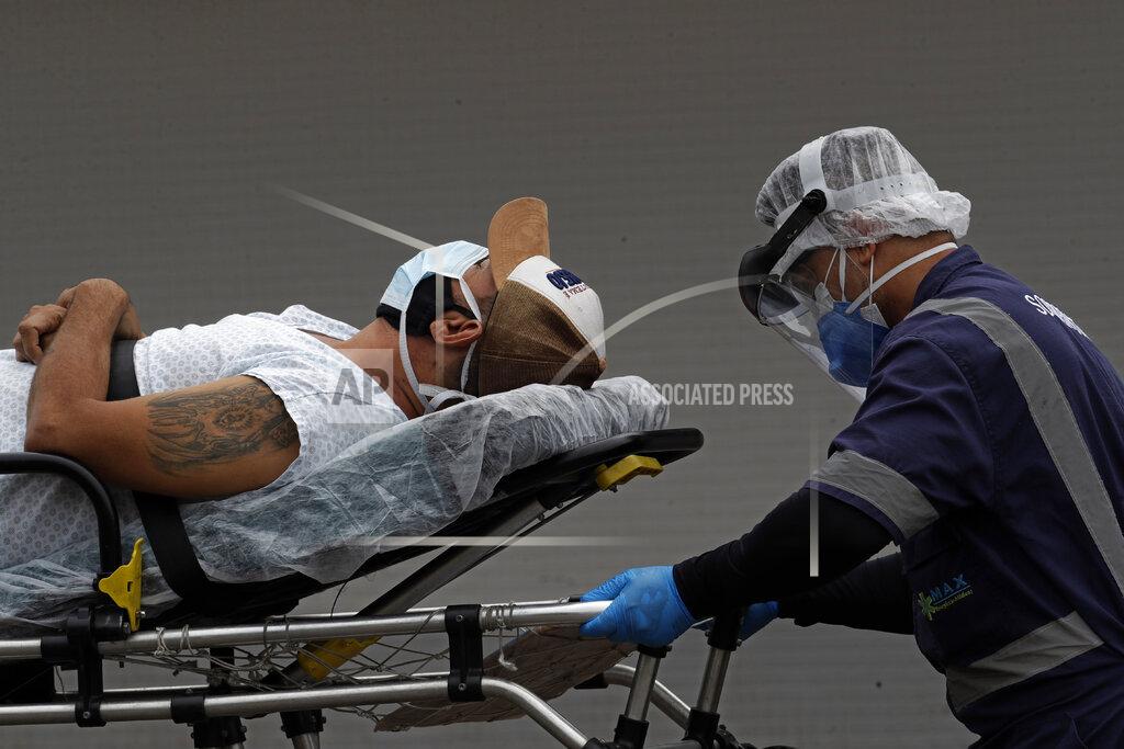 A healthcare worker transfers a patient suspected of having COVID-19 from an ambulance into the HRAN public hospital in Brasilia, Brazil, Thursday, April 29, 2021. (AP Photo/Eraldo Peres)