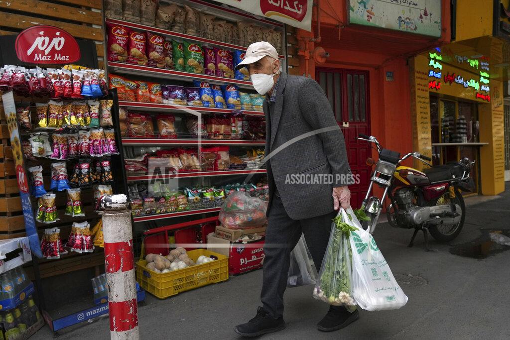 Vahid Salemi An elderly man carries his shopping in front of a grocery store in Tehran, Iran, Wednesday, May 11, 2022. Iran abruptly raised prices as much as 300% for a variety of staples such as cooking oil, chicken, eggs and milk on Thursday. (AP Photo/Vahid Salemi)