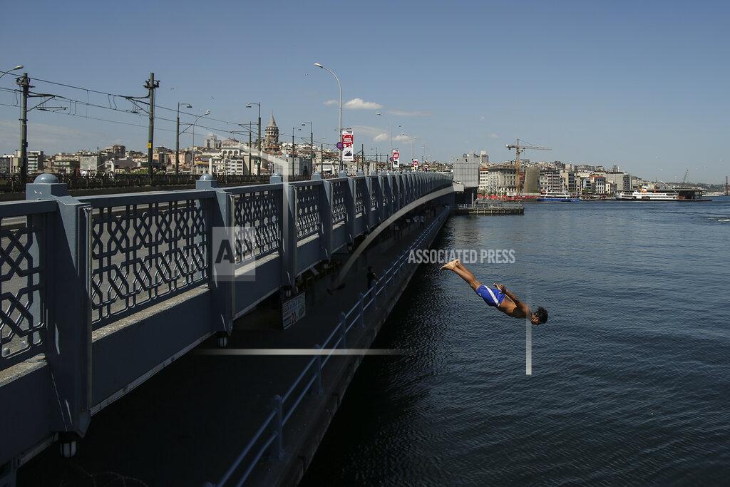 Emrah Gurel Backdropped by Galata Tower, a youth jumps from the Galata Bridge into the Golden Horn leading to the Bosphorus Strait separating Europe and Asia, in Istanbul, Friday, May 14, 2021. Turkey is in the final days of a full coronavirus lockdown and the government has ordered people to stay home and businesses to close amid a huge surge in new daily infections. But millions of workers are exempt and so are foreign tourists. Turkey is courting international tourists during an economic downturn and needs the foreign currencies that tourism brings to help the economy as the Turkish lira continues to sink. (AP Photo/Emrah Gurel)