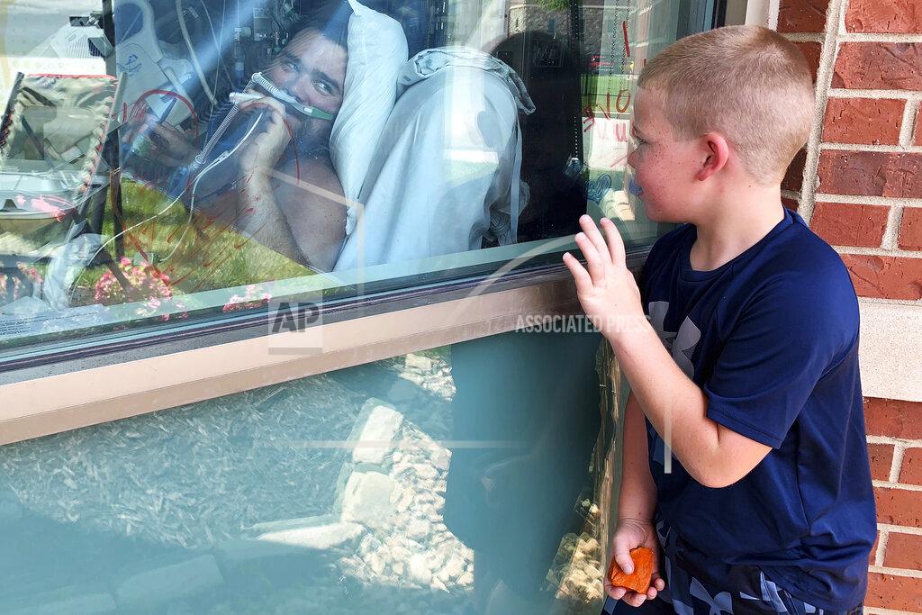 Sarah Blake Morgan Six-year-old Brody Barker waves to his father, Daryl, from outside his hospital room on Monday, July 26, 2021, in Osage Beach, Mo. Brody and his mother, Billie, have spent nearly three weeks camped outside Lake Regional Hospital's Intensive Care Unit as Barker recovers from COVID-19. "I think that him being able to see us made him fight more," she said. (AP Photo/Sarah Blake Morgan)