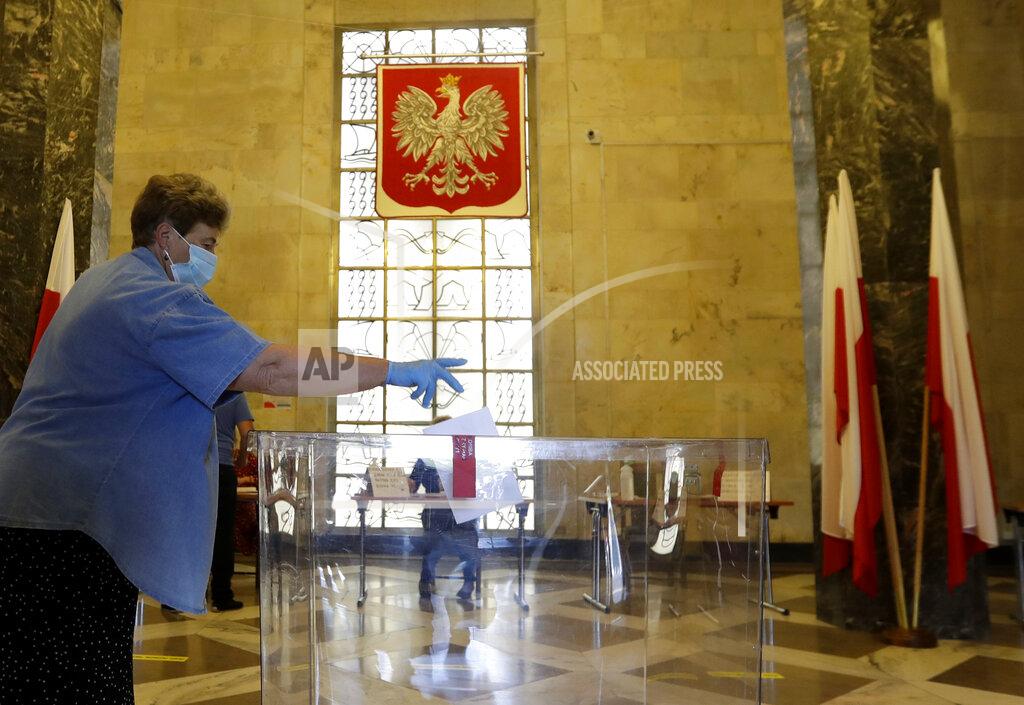 Petr David Josek A resident, wearing face mask and protective gloves, casts a vote during presidential election in Warsaw, Poland, Sunday, June 28, 2020. The election will test the popularity of incumbent President Andrzej Duda who is seeking a second term and of the conservative ruling party that backs him. (AP Photo/Petr David Josek)