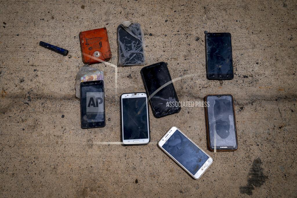 Emilio Morenatti Wet phones and other items are placed on the ground by police officers as they inspect a boat where 15 Malians were found dead adrift in the Atlantic on Thursday, Aug. 20, 2020 in Gran Canaria island, Spain. The 15 lifeless men were spotted inside a boat on August 19 by a Spanish plane 80 nautical miles (148 kilometers, 92 miles) from the island of Gran Canaria. Police collected what was left behind as evidence: a wallet, a dozen cell phones, windbreakers and waterproof boots. (AP Photo/Emilio Morenatti)