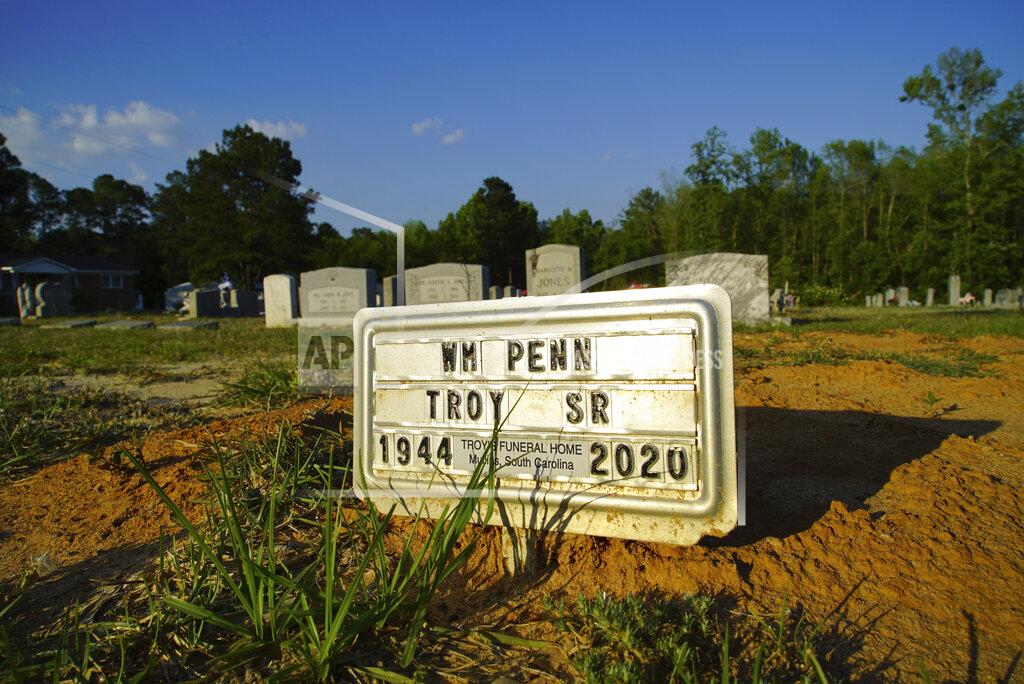 Allen G. Breed A tin plaque marks the grave of William Penn Troy Sr. at Hillcrest Cemetery outside Mullins, S.C., on Sunday, May 23, 2021. Troy died of COVID-19 in August 2020, one of many Black funeral home directors to succumb during the pandemic. (AP Photo/Allen G. Breed)