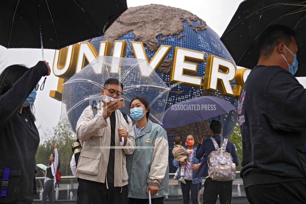 Andy Wong People wearing face masks to help protect themselves from the coronavirus pose for a selfie with an icon near the entrance to the Universal Studios Beijing in Beijing, Monday, Sept. 20, 2021. Thousands of people brave the rain visit to the newest location of the global brand of theme parks which officially opens on Monday. (AP Photo/Andy Wong)