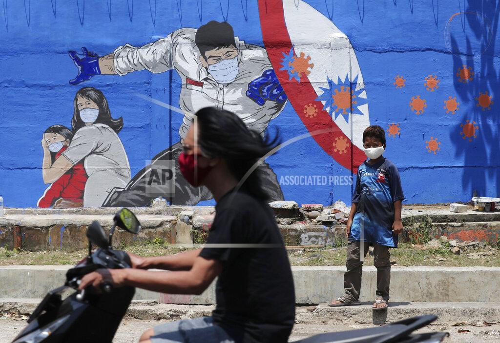 Tatan Syuflana A young boy stands near a coronavirus-themed mural as a motorist rides past by in Jakarta, Indonesia, Thursday, Aug. 27, 2020. (AP Photo/Tatan Syuflana)