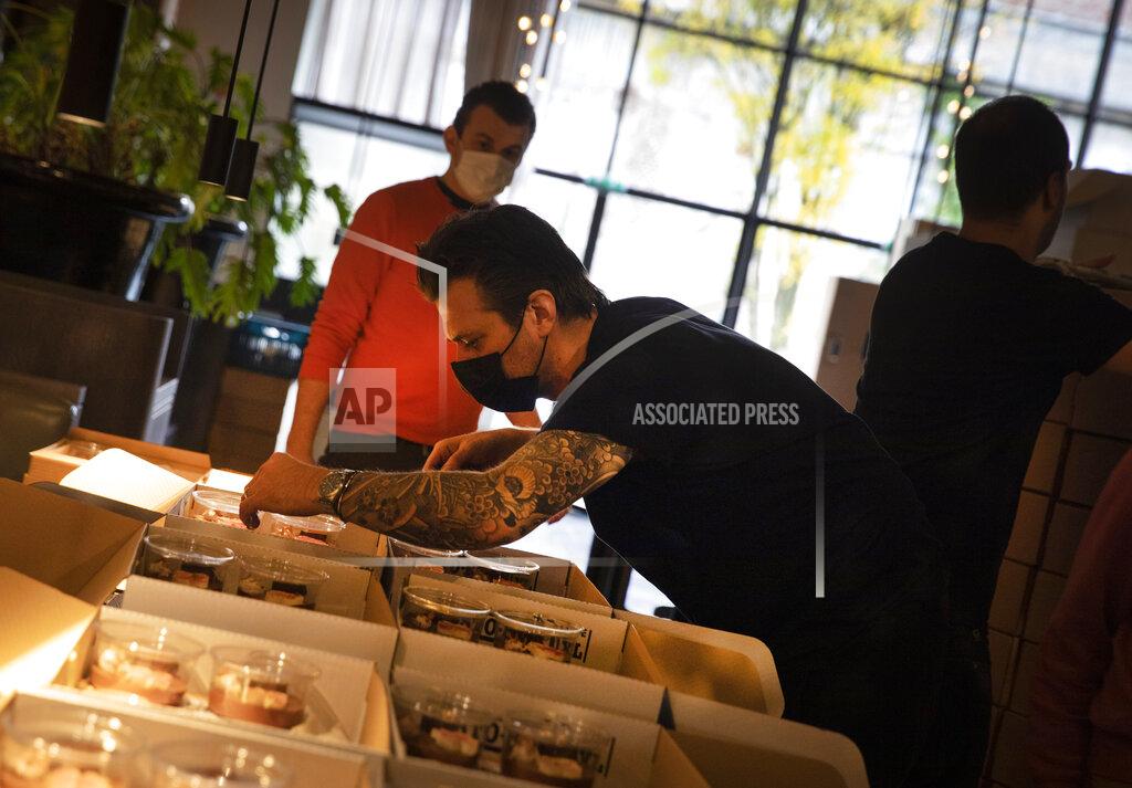Virginia Mayo Chef Sergio Herman, center, puts the finishing touches on nearly 600 take-away orders at his restaurant, Le Pristine, in Antwerp, Belgium, Saturday, Nov. 7, 2020. Of all the many challenges the pandemic throws up for all kinds of professions, this one has been particularly tough: How to put a three-star chef into a takeout box. (AP Photo/Virginia Mayo)