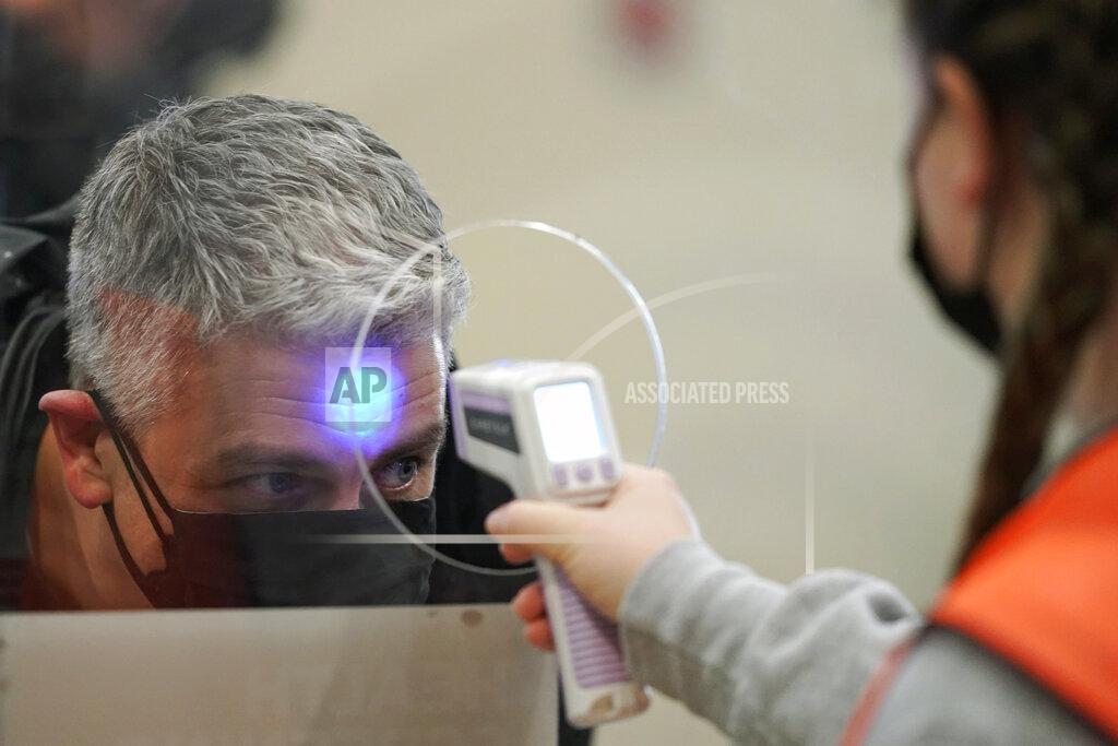 Ted S. Warren HOLD FOR STORY BY TERRY TANG AND MANUEL VALDES - A volunteer worker has their temperature taken as they arrive at a mass vaccination clinic at Seattle University, Friday, Feb. 26, 2021, in Seattle. As states ramp up vaccination distribution in the fight against the coronavirus, volunteers are needed to do everything from direct traffic to check people in to keep vaccination sites running smoothly. In return for their work, they're often given a shot — including those who are young and healthy and may not have otherwise been able to receive the shot until later in the year. (AP Photo/Ted S. Warren)