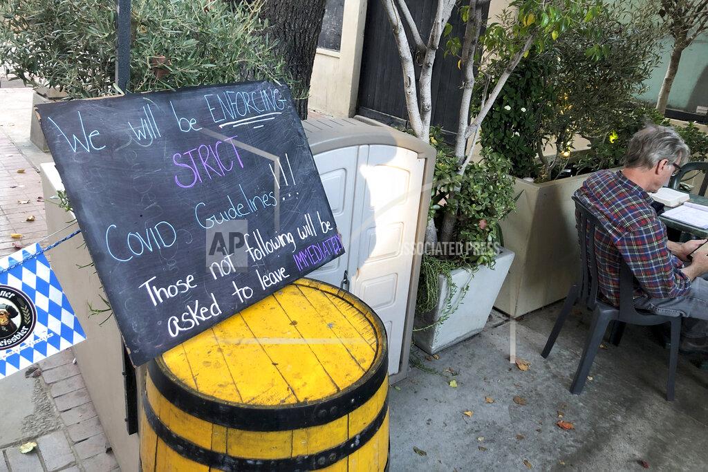 Chris Weber A sign advises patrons to adhere to COVID-19 guidelines at Lucky Baldwin's pub on Monday, Nov. 30, 2020 in Pasadena, Calif. It was a rare sight after restaurants in Los Angeles County were ordered to halt serving food to diners to stop the spread of coronavirus: tables and chairs were set up outdoors in Pasadena. The city in the Los Angeles suburbs has become an island in the center of the nation's most populous county, where a surge of COVID-19 cases last week led to a three-week end to outdoor dining and California's first stay-home order since the pandemic began to spread across the state in March. (AP Photo/Christopher Weber)