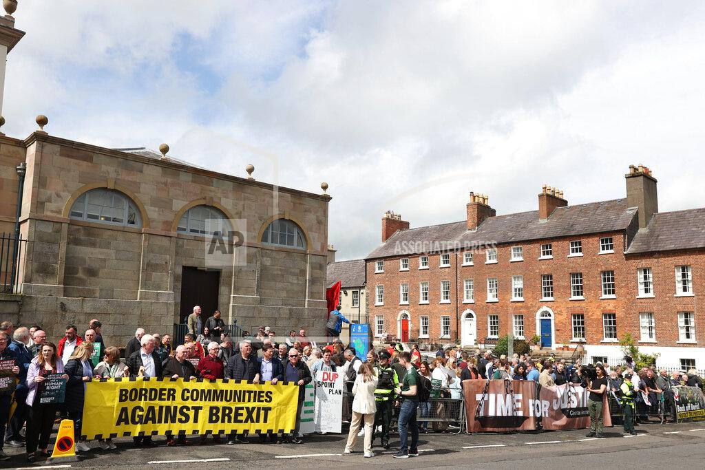 Liam Mcburney People demonstrate outside Hillsborough Castle ahead of a visit by British Prime Minister Boris Johnson, in Hillsborough, Northern Ireland, Monday, May 16, 2022. Johnson on Monday renewed British threats to break a Brexit agreement with the European Union, blaming it for a political crisis that's blocking the formation of a new government in Northern Ireland. (Liam McBurney/PA Wire/PA via AP)