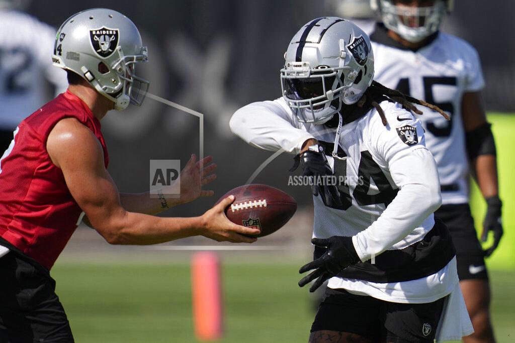 John Locher Las Vegas Raiders' Derek Carr hands the ball off to Brandon Bolden during NFL football training camp, Friday, July 22, 2022, in Henderson, Nev. (AP Photo/John Locher)