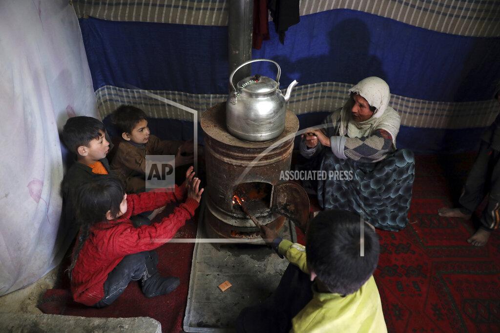 Rahmat Gul Internally displaced children sit around a stove to keep warm in a temporary shelter in the city of Kabul, Afghanistan, Wednesday, Dec. 30, 2020. Save the Children has warned that more than 300,000 Afghan children face freezing winter conditions that could lead to illness, in the worst cases death, without proper winter clothing and heating. (AP Photo/Rahmat Gul)