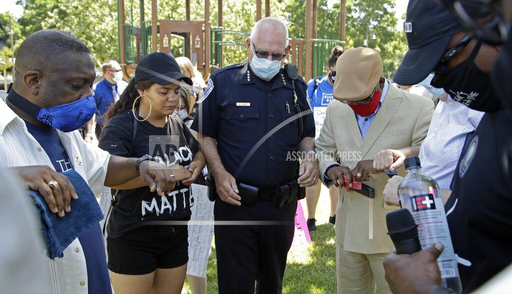 Ben Margot Local Pastors touch elbows with Fairfield Police Chief Walter Tibbet, center, during 'Taking a knee for Justice and Prayer' service, Wednesday, June 3, 2020, in Fairfield, Calif. (AP Photo/Ben Margot)
