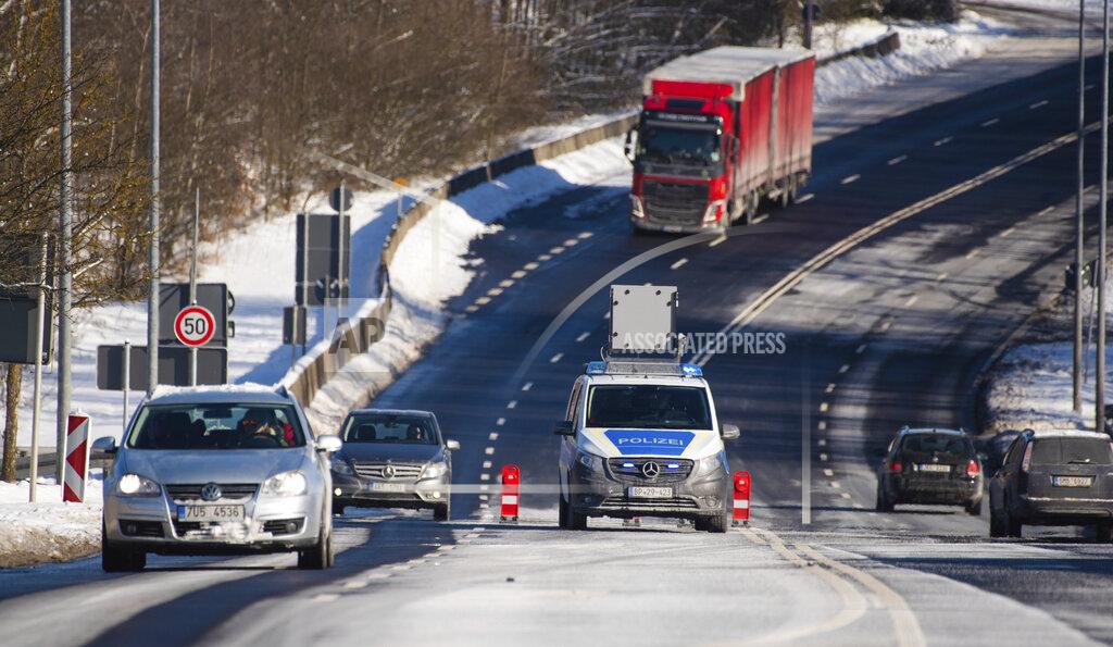 Nicolas Armer Vehicles pass a police car at the German border to the Czech Republic near Schirnding, Germany, Friday, Feb. 12, 2021. (Nicolas Armer/dpa via AP)