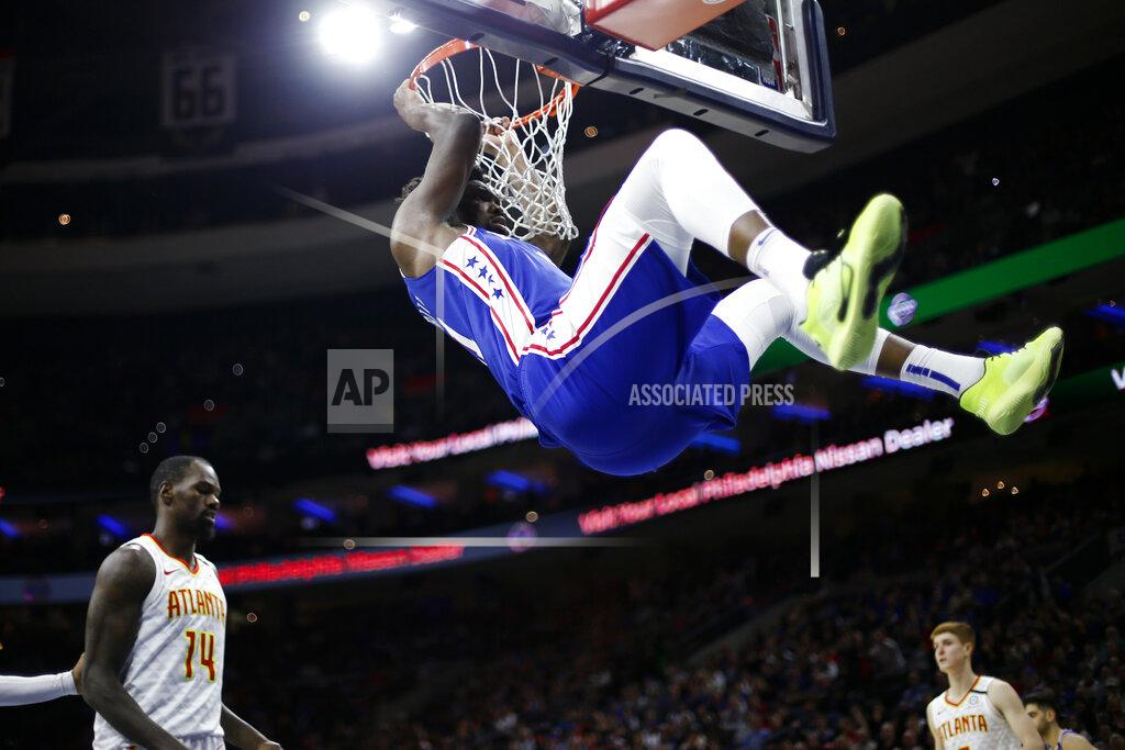 Matt Slocum FILE - In this Feb. 24, 2020, file photo, Philadelphia 76ers' Joel Embiid, top, hangs from the rim after a dunk past Atlanta Hawks' Dewayne Dedmon during the second half of an NBA basketball game in Philadelphia. Embiid is hurting, and that's a cause for concern as the 76ers get set to restart their season this week. The All-Star starting center sat out Philadelphia's scrimmage against Oklahoma City on Sunday, July 26, 2020, with right calf tightness, something 76ers coach Brett Brown hopes is merely a minor blip. (AP Photo/Matt Slocum, File)
