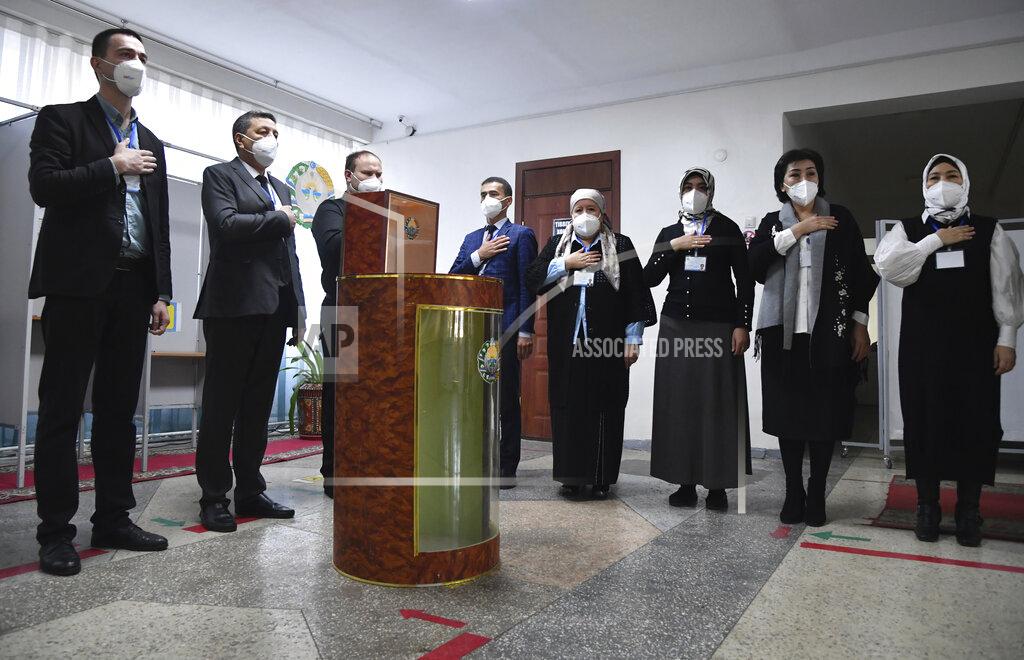 Uncredited Members of an election commission listen to the national anthem at a polling station during the presidential election in Tashkent, Uzbekistan, Sunday, Oct. 24, 2021. Uzbekistan's President, Shavkat Mirziyoyev, who has relaxed many of the policies of his dictatorial predecessor but has made little effort at political reform, is expected to win a new term by a landslide against weak competition in an election Sunday. (AP Photo)