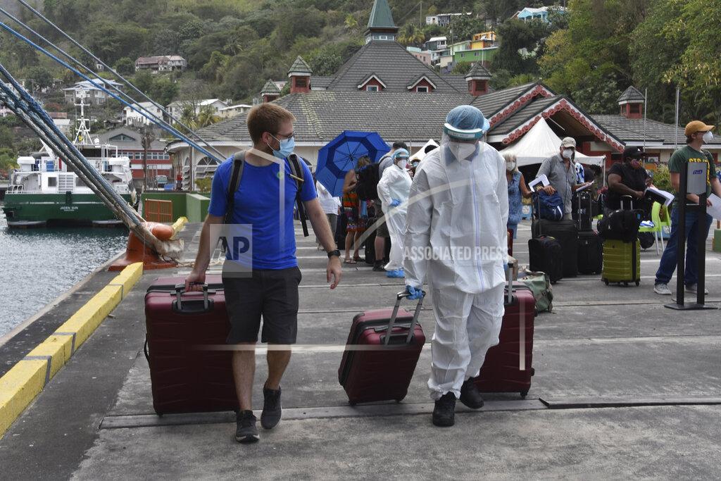 Orvil Samuel A healthcare worker helps an evacuee with his luggage as British, Canadian and U.S. nationals wait to board the Royal Caribbean cruise ship Reflection, in Kingstown, on the eastern Caribbean island of St. Vincent, Friday, April 16, 2021. La Soufriere volcano has shot out another explosive burst of gas and ash Friday morning as the cruise ship arrived to evacuate some of the foreigners who had been stuck on a St. Vincent island by a week of violent eruptions. (AP Photo/Orvil Samuel)