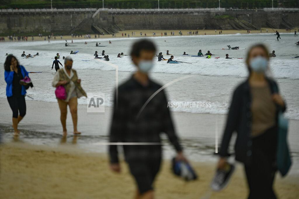 Alvaro Barrientos People walk along La Concha beach, after lockdown restrictions were lifted, in San Sebastian, northern Spain, Sunday, May 9, 2021. Impromptu street celebrations erupted across Spain as the clock struck midnight on Saturday, when a six-month-long national state of emergency to contain the spread of coronavirus ended and many nighttime curfews were lifted. (AP Photo/Alvaro Barrientos)