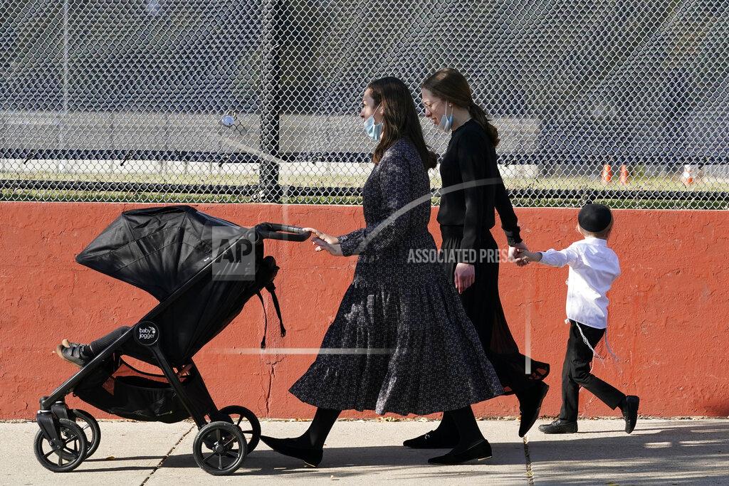 Kathy Willens FILE - In this Oct. 4, 2020, file photo, two women walk with children during the Jewish holiday of Sukkot in the Borough Park neighborhood of the Brooklyn borough of New York. Amid a new surge of COVID-19 in New York’s Orthodox Jewish communities, many residents are reviving health measures that some had abandoned over the summer – social distancing, wearing masks. For many, there’s also a return of anger: They feel the city is singling them out for criticism that other groups avoid. (AP Photo/Kathy Willens, File)