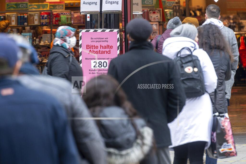 Peter Kneffel Costumers line up near a sign with the inscription 'Please keep your distance - At the moment we can only let 280 customers into the store' in front of the entrance of a department store in Munich, Germany, Dec. 10, 2020. (Peter Kneffel/dpa via AP)