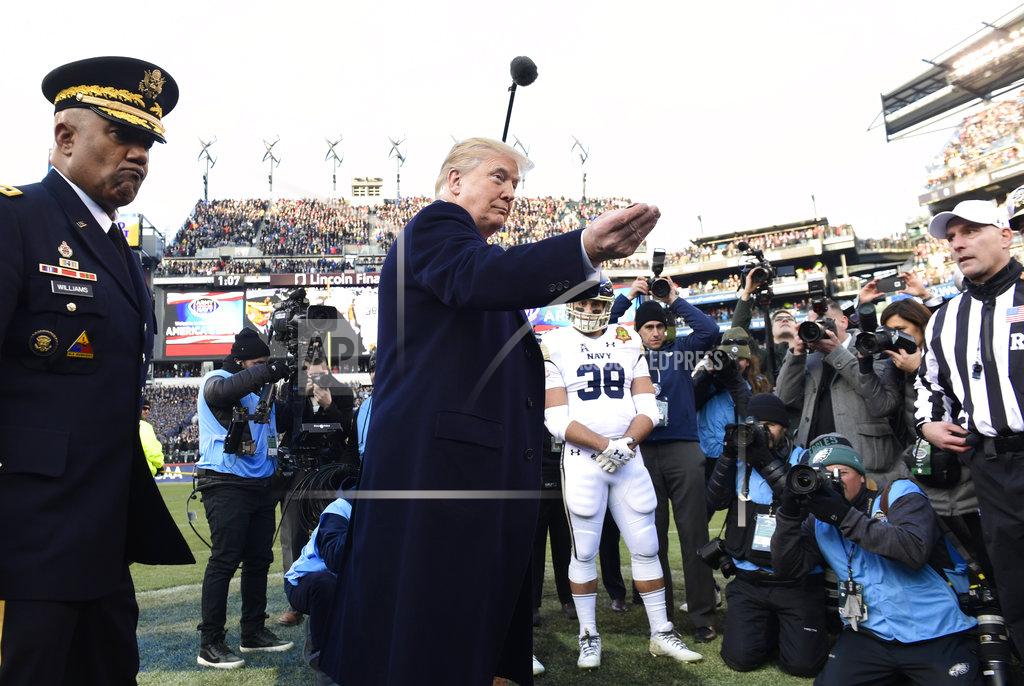 Susan Walsh President Donald Trump, center, hold out the coin for the coin toss at the Army-Navy NCAA college football game in Philadelphia, Saturday, Dec. 8, 2018. (AP Photo/Susan Walsh)