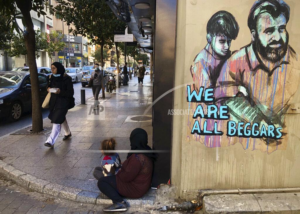 Hussein Malla People pass next of a woman, center, who is sits on the ground with her daughter begging on Beirut's commercial Hamra Street, in Beirut, Lebanon, Tuesday, March 16, 2021. More than half the population now lives in poverty, while an intractable political crisis heralds further collapse and Lebanese are gripped by fear for the future. (AP Photo/Hussein Malla)