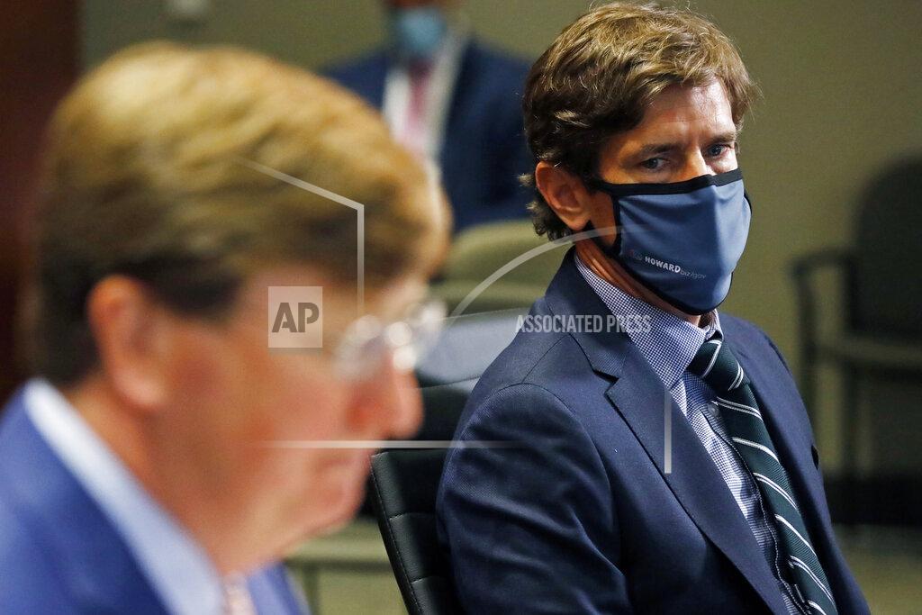 Mississippi State Health Officer Dr. Thomas Dobbs, right, listens as Gov. Tate Reeves responds to a reporter's question regarding his executive order mandating that all adults and students wear masks in schools, unless there's a medical reason that prevents them from doing so, during the governor's COVID-19 press briefing in Jackson, Miss., Tuesday, Aug. 4, 2020. State officials provided reporters an update on the coronavirus and the state's ongoing strategy to limit transmission in public schools. (AP Photo/Rogelio V. Solis)