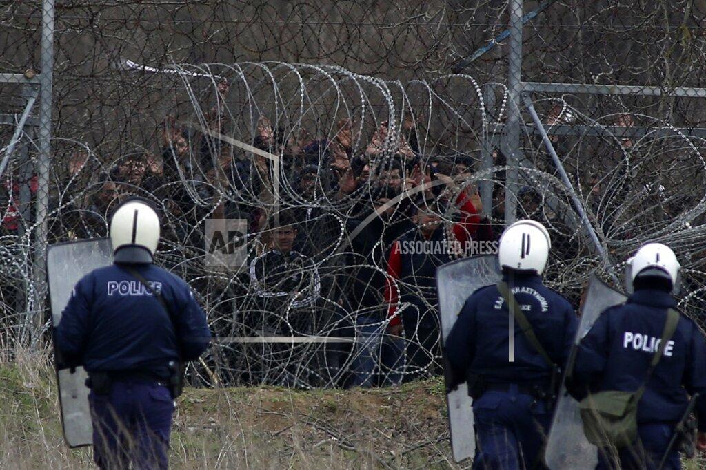 Giannis Papanikos FILE - In this Wednesday, March 4, 2020 file photo, Greek riot police guard as migrants stand on a fence trying to enter Greece from Turkey at the Greek-Turkish border in Kastanies. Five years on, the deal between European Union and Turkey is no longer working but at a summit next week EU leaders will discuss ways to improve relations with Turkey and could try to revive the agreement. (AP Photo/Giannis Papanikos, File)