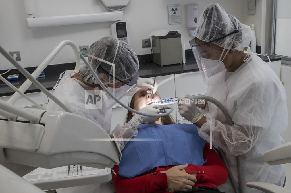Michel Euler In this Wednesday, May 13, 2020 photo, dentist Sabrine Jendoubi, left, and her dental assistant Margot Daussat inspect the teeth of patient Veronique Guillot, during a dental appointment, at a dental office in Paris. Those with toothache that suffered through France's two-month lockdown, finally have hope to end the pain. Dental practices are cautiously re-opening and non-emergency dentist appointments are now permitted around the country, as the French government eased confinement restrictions from Monday. (AP Photo/Michel Euler)