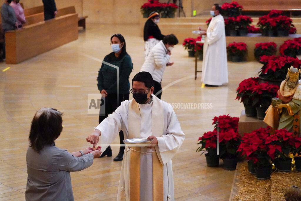 Ashley Landis Worshipers receive communion during a Christmas Eve Mass inside the Cathedral of Our Lady of the Angels Thursday, Dec 24, 2020, in Los Angeles. California became the first state to record 2 million confirmed coronavirus cases, reaching the milestone on Christmas Eve as nearly the entire state was under a strict stay-at-home order and hospitals were flooded with the largest crush of cases since the pandemic began. (AP Photo/Ashley Landis)