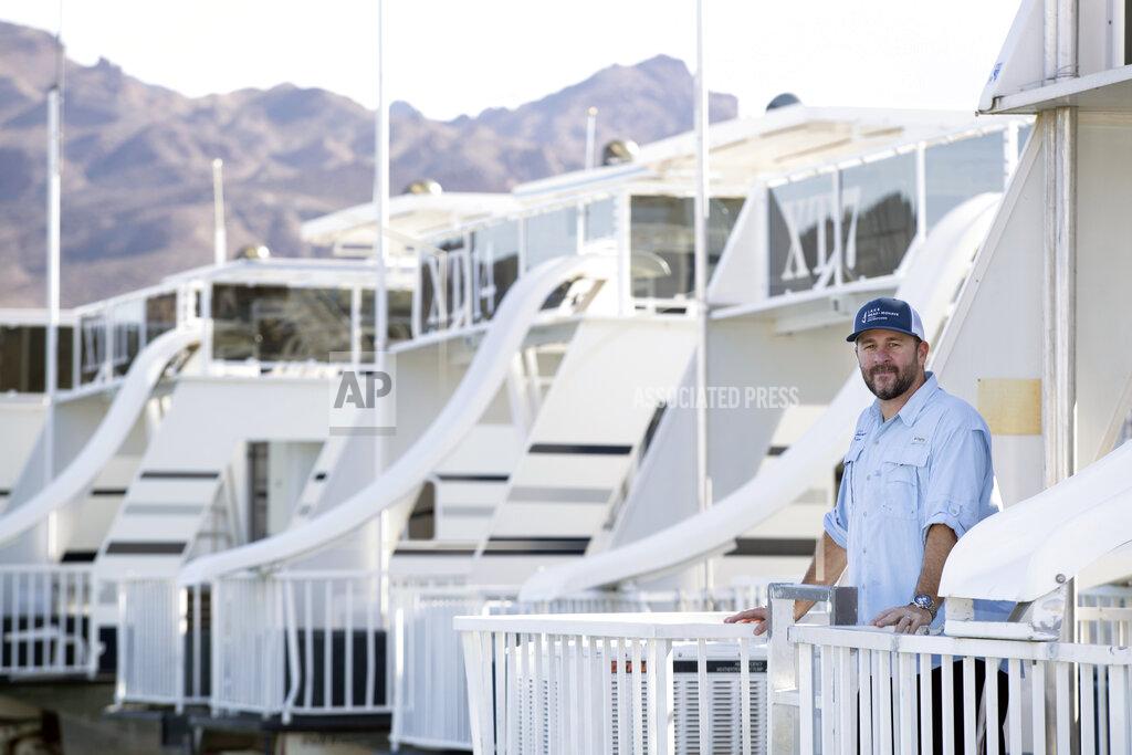 Steve Marcus Chad Taylor, director of sales and marketing for Lake Mead Mohave Adventures, poses by houseboats at the Callville Bay Marina in the Lake Mead National Recreation Area Tuesday, Sept. 14, 2021 in Las Vegas. Some businesses that depend on the Colorado River caught a wave of customers after coronavirus pandemic closures closed schools and offices. Taylor says that receding water levels at Lake Mead, the river’s drought-stricken reservoir, have him constantly moving docks farther into Callville Bay. (Steve Marcus/Las Vegas Sun via AP)