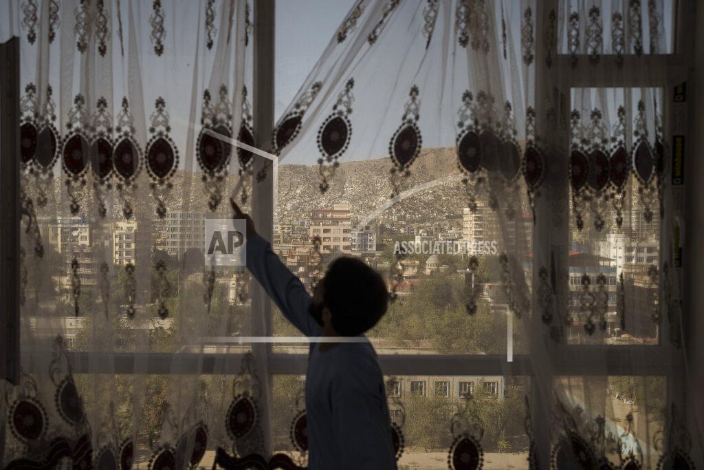 Felipe Dana Mohammed Zakir closes the curtains of his family home, overlooking Kabul, Afghanistan, Friday, Sept. 17, 2021. Zakir's bother, Zaki Anwari, was a 17-year-old soccer player who died after trying to board a departing U.S. Air Force C-17 on Aug. 16 at Kabul's airport. (AP Photo/Felipe Dana)