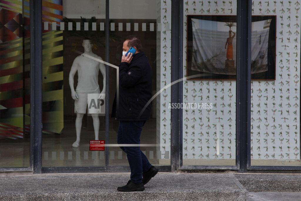 Petros Karadjias A man wearing face mask speaks from his cell phone as walks outside of a shop at a shopping street in central Nicosia, Friday, Jan. 8, 2021. Cyprus is returning to lockdown mode for the remainder of the month with daytime restrictions on movement and a shuttering of schools after the country's health minister conceded that a raft of tough measures already in place including a night-time curfew weren't enough to curtail the spread of the coronavirus. (AP Photo/Petros Karadjias)