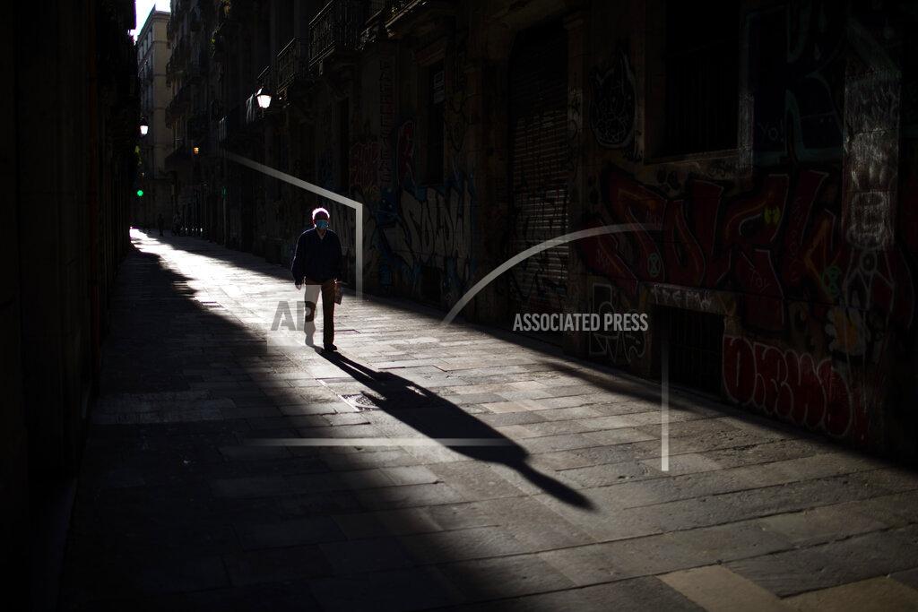 A man walks along an empty street in downtown Barcelona, Spain, Saturday, April 25, 2020 as the lockdown to combat the spread of coronavirus continues. (AP Photo/Emilio Morenatti)