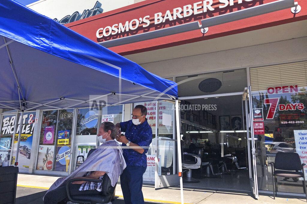 Ben Margot FILE - In this July 22, 2020 file photo, a customer of Cosmo's barber shop receives a haircut in the parking lot in front of the shop in Pleasanton, Calif. The coronavirus and the drastic measures put in place by government officials to try to control its spread had a severe toll on many small businesses in the U.S. Restaurants, hair salons, event planners and other businesses that rely on people being in close proximity were particularly hard-hit, as were those tied to tourism. (AP Photo/Ben Margot)
