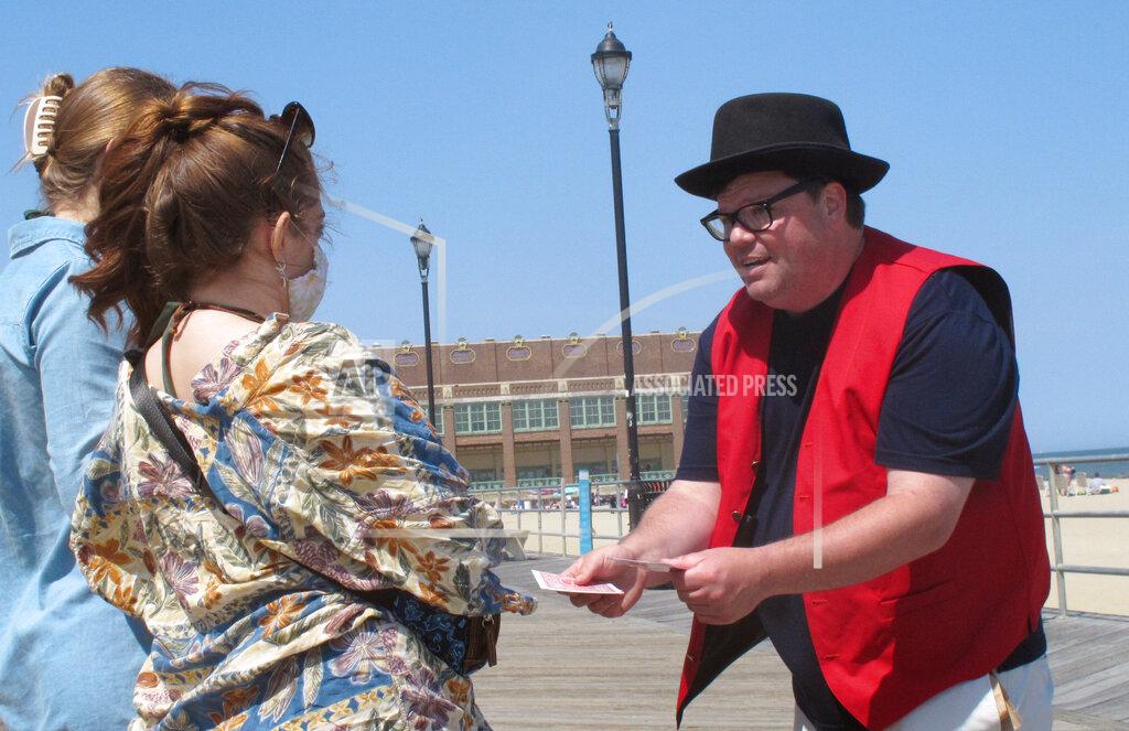 Wayne Parry Magician Robert Francis performs a card trick on the boardwalk in Asbury Park N.J. on Friday, May 21, 2021. Businesses and residents alike expect this summer at the Jersey Shore to be busier than last year as more people get vaccinated and COVID19 restrictions are scaled back or eliminated. (AP Photo/Wayne Parry)