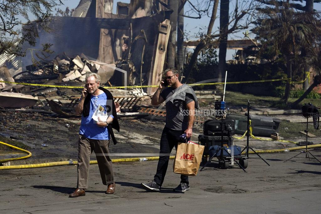 Marcio Jose Sanchez Residents talk on their cell phones as they walk past a fire-damaged property in the aftermath of the Coastal Fire Thursday, May 12, 2022, in Laguna Niguel, Calif. (AP Photo/Marcio Jose Sanchez)