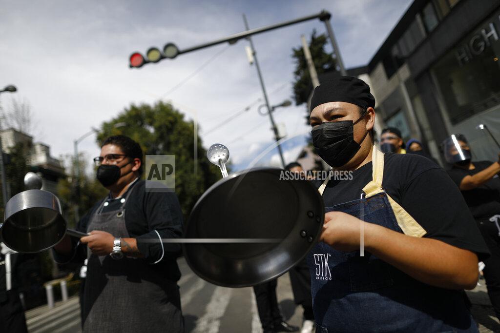 Rebecca Blackwell Restaurant workers bang metal pots as more than a hundred employees from multiple restaurants blocked a street in the Polanco neighborhood to protest against COVID-19 "red alert" restrictions that have closed on-site dining, in Mexico City, Tuesday, Jan. 12, 2021. More than three weeks into Mexico City's second pandemic shutdown, restaurateurs desperate to save their businesses and maintain their employees are uniting under the slogan "Open or Die" ("Abrir o morir" in Spanish), to pressure the city government to allow them to operate with limited seating and protective health measures. (AP Photo/Rebecca Blackwell)