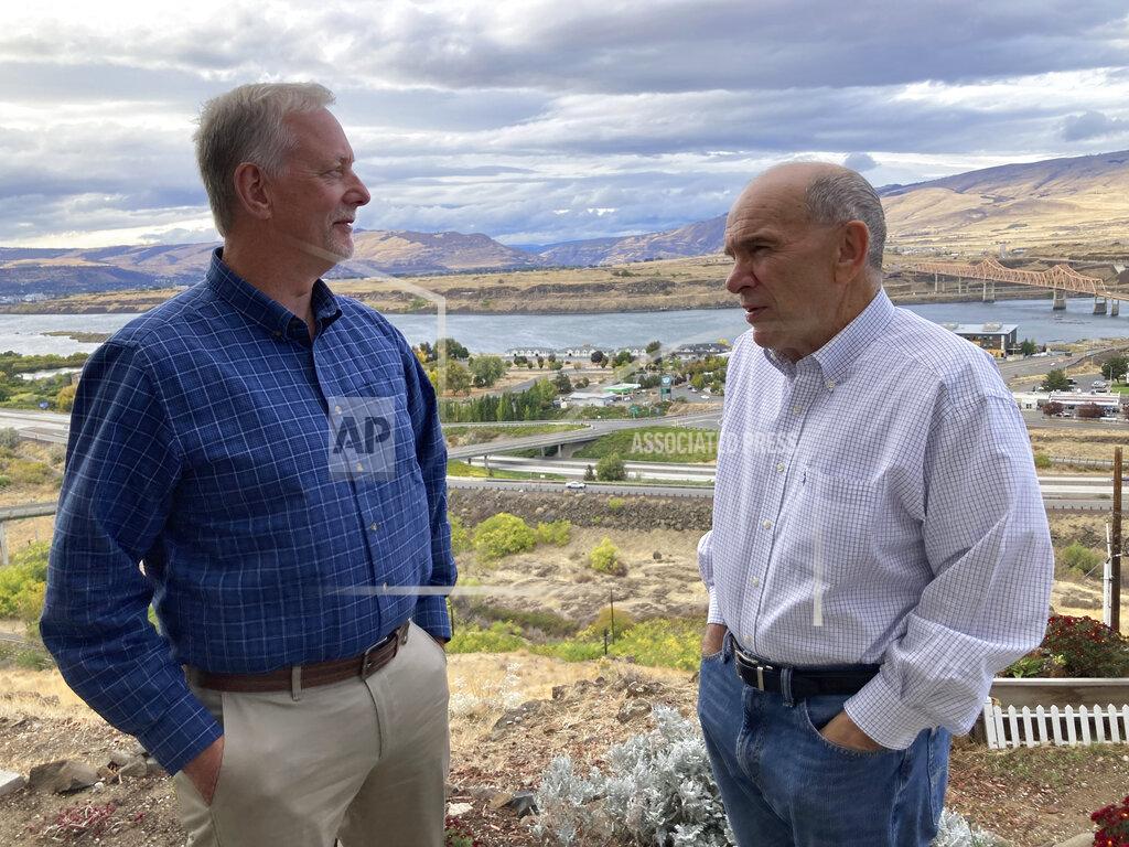 Andrew Selsky In this Tuesday, Oct. 5, 2021, photo, The Dalles city Public Works Department Director Dave Anderson, left, and Mayor Richard Mays pose for photos with the Columbia River in The Dalles, Oregon. Mays helped negotiate a proposal by Google to build new data centers in the town. The data centers require a lot of water to cool their servers, and would use groundwater and surface water, but not any water from the Columbia River. (AP Photo/Andrew Selsky)