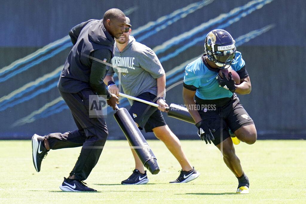 John Raoux Jacksonville Jaguars running back Travis Etienne Jr., right, runs past coaches as he preforms a drill during an NFL football rookie minicamp, Saturday, May 15, 2021, in Jacksonville, Fla. (AP Photo/John Raoux)