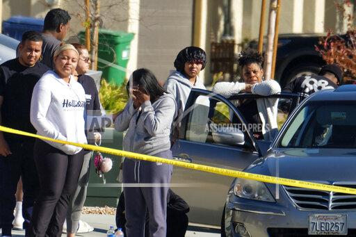 Neighbors react near a home where five bodies were found in the city of Lancaster in the high desert Antelope Valley north of Los Angeles, Monday, Nov. 29, 2021. A Los Angeles County Sheriff's Department statement says deputies found a woman, a girl and three boys with gunshot wounds and paramedics pronounced them dead at the scene. The department says the children's father showed up at the Lancaster sheriff's station and was arrested on suspicion of five murders after being interviewed by detectives. (AP Photo/Ringo H.W. Chiu)